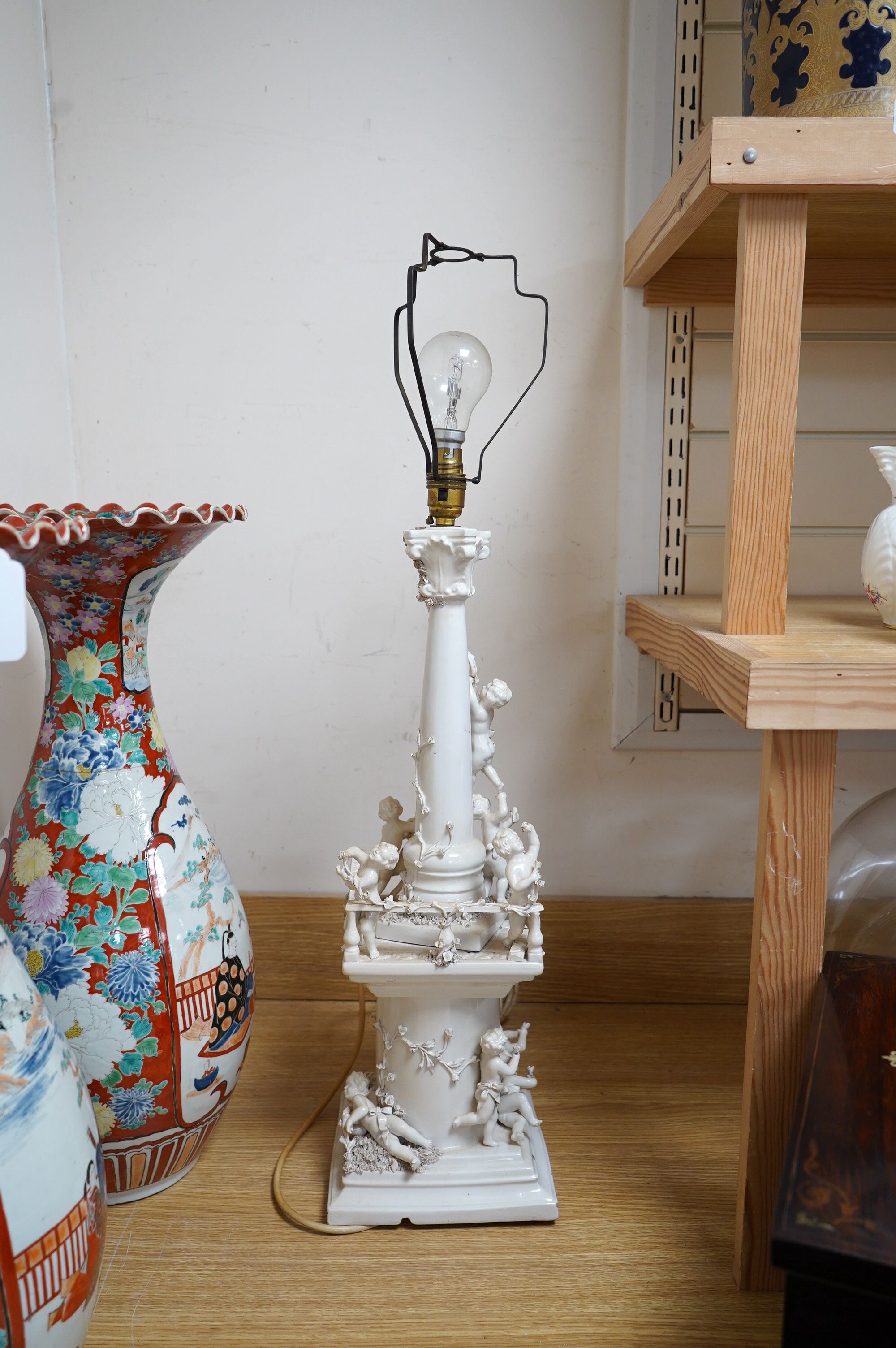 A modern Italian white maiolica ‘playing putti’ table lamp, 55cm. Condition - fair